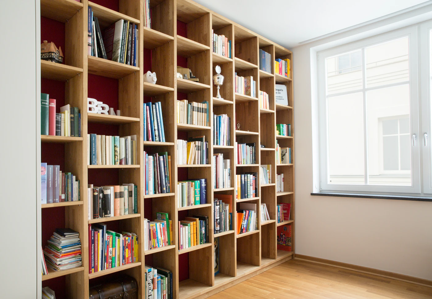 Tall wooden bookshelves filled with books beside a bright window