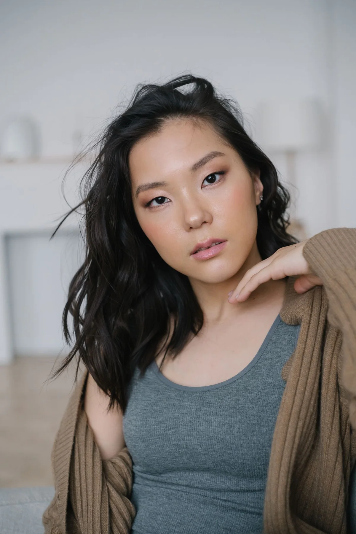 A woman in an open brown cardigan over a grey tank top.