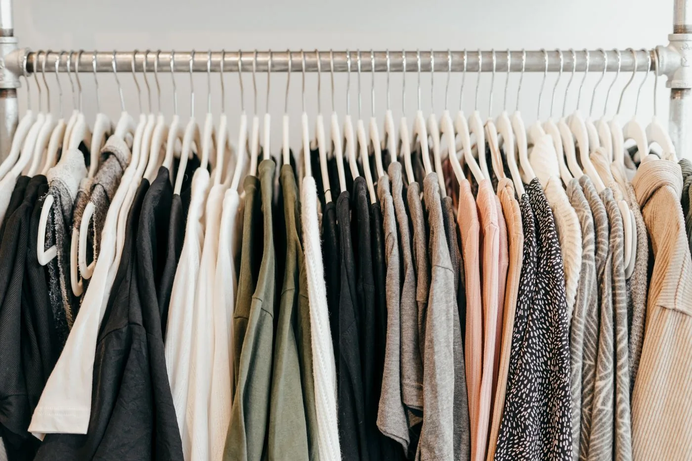 Pale and dark garments arranged on a long clothing rail.