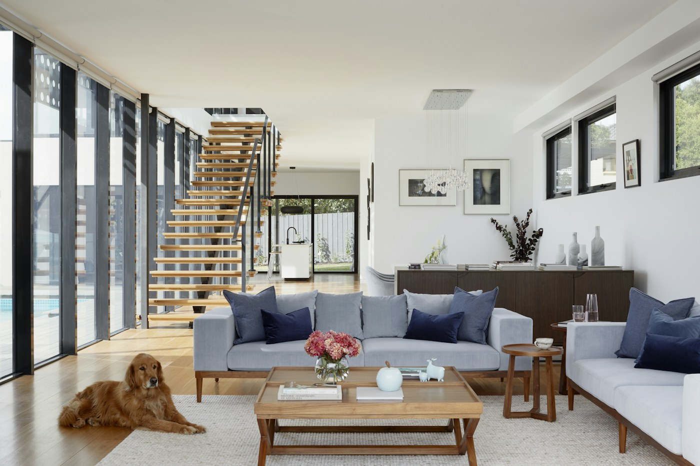 Light-filled living room with neutral furnishings and an open staircase